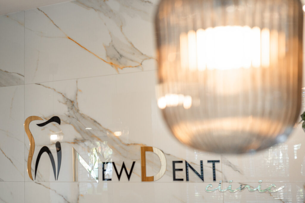 Logo New Dent Clinic w recepcji kliniki na Ratajach